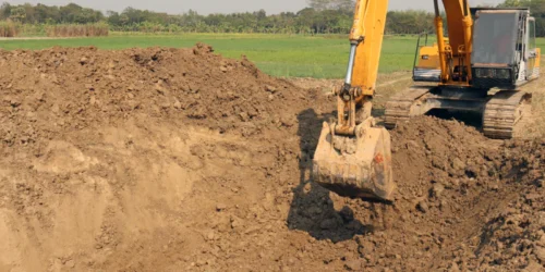 yellow excavator digging land